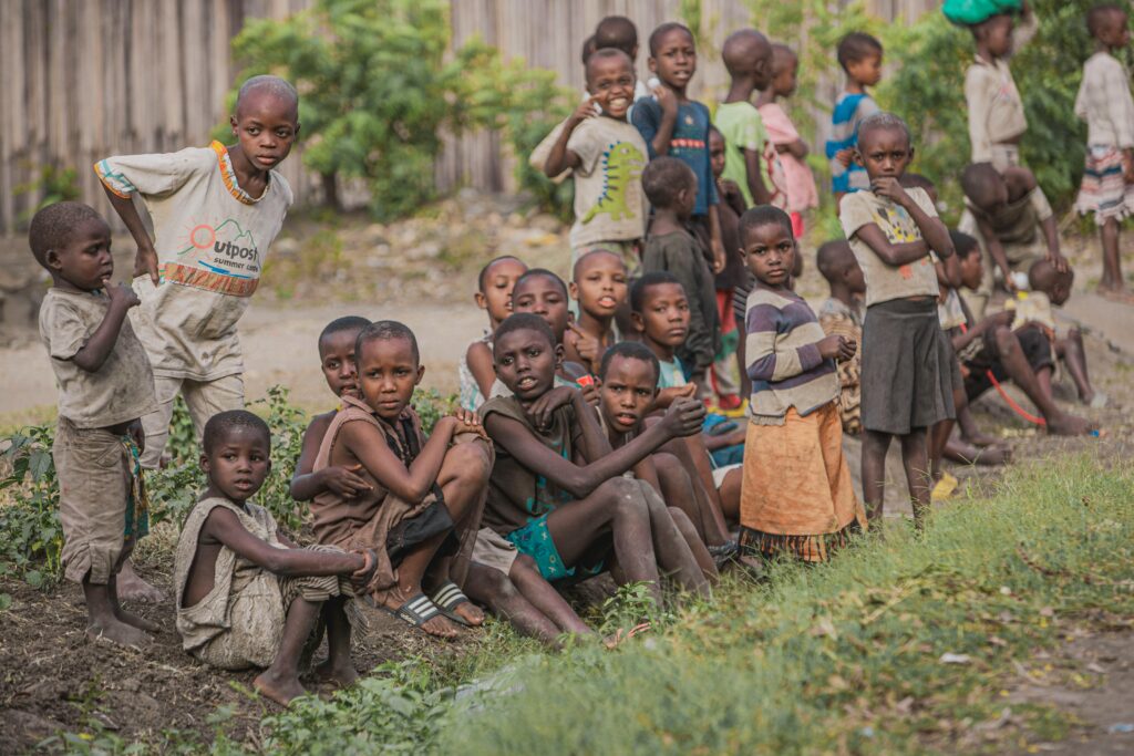 A group of children sitting and standing together outdoors, showcasing community and togetherness.